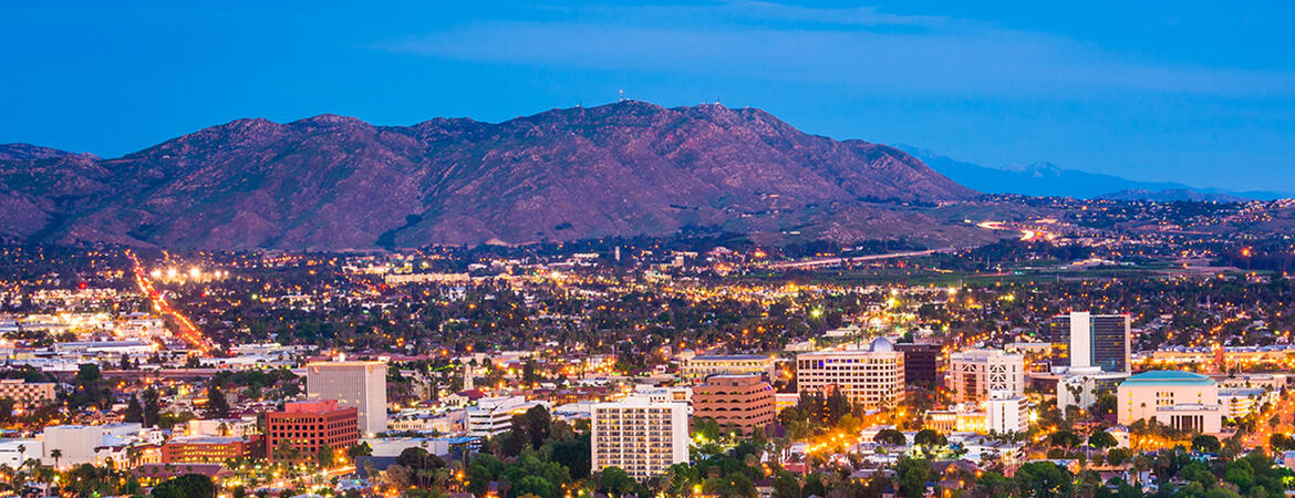 Evening aerial view of Riverside, California, with city lights and surrounding mountains.