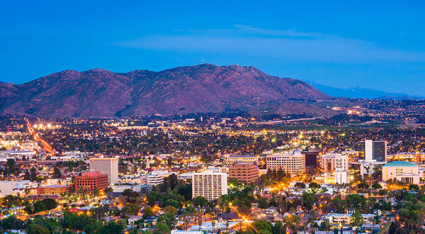 Evening aerial view of Riverside, California, with city lights and surrounding mountains.