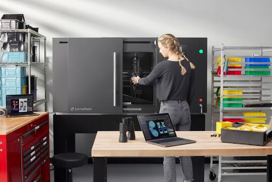 A technician operates a Lumafield Neptune industrial CT scanner in a lab or manufacturing workspace.